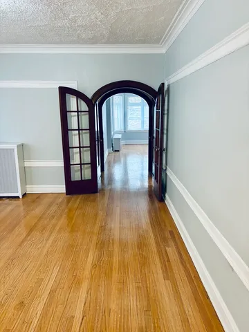 a view of empty room with wooden floor and fan