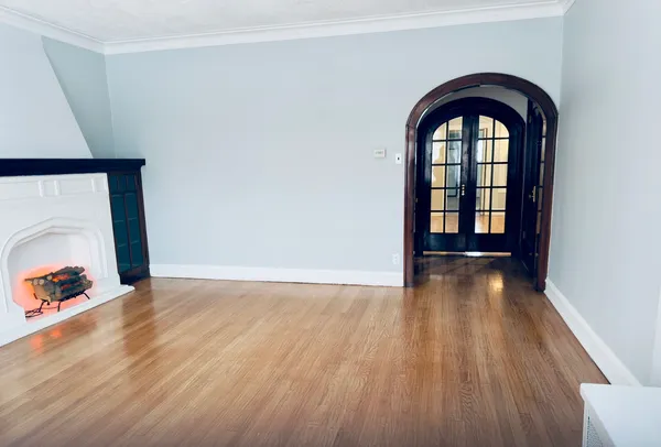 an empty room with wooden floor and natural light