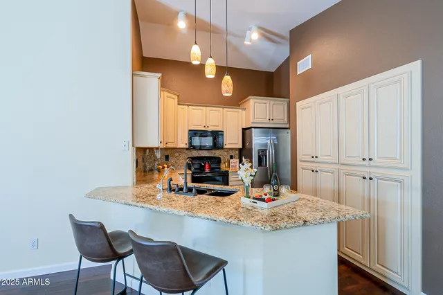 a kitchen with stainless steel appliances a dining table chairs and granite counter tops