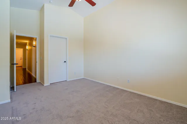 an empty room with closet and a chandelier fan
