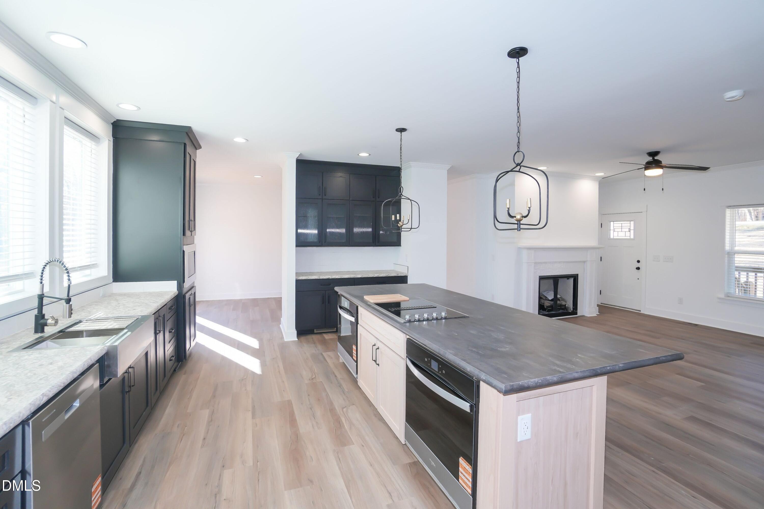 5430 Bass Mountain Road Snow Camp, NC 27349 - Photo 7 of 14 a kitchen with a stove center island a sink dishwasher and a fireplace with wooden floor