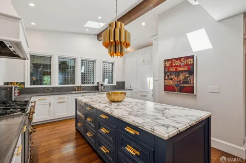 a kitchen with stainless steel appliances granite countertop a sink dishwasher and a dining table with wooden floor