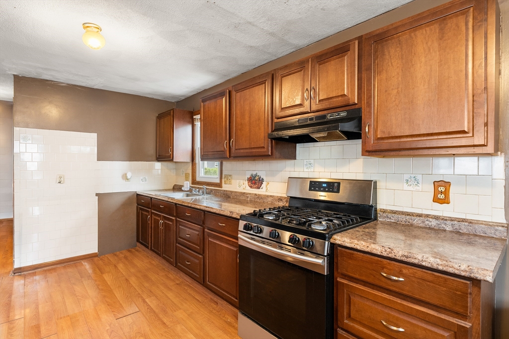23 Logan Street Lynn, MA 01902 - Photo 8 of 27 a kitchen with stainless steel appliances granite countertop a stove a sink dishwasher and a microwave oven with cabinets