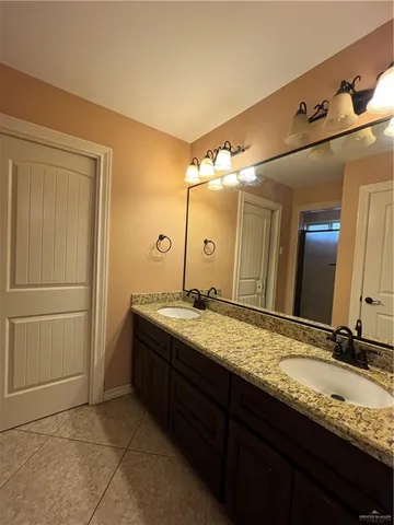 a bathroom with a granite countertop double vanity sink and mirror