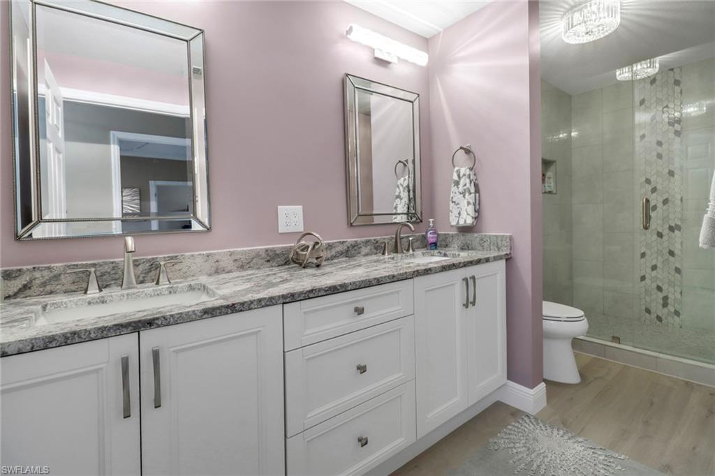 20261 Estero Gardens Circle, Unit 104 Estero, FL 33928 - Photo 16 of 50 Bathroom featuring toilet, wood-type flooring, an enclosed shower, and double vanity