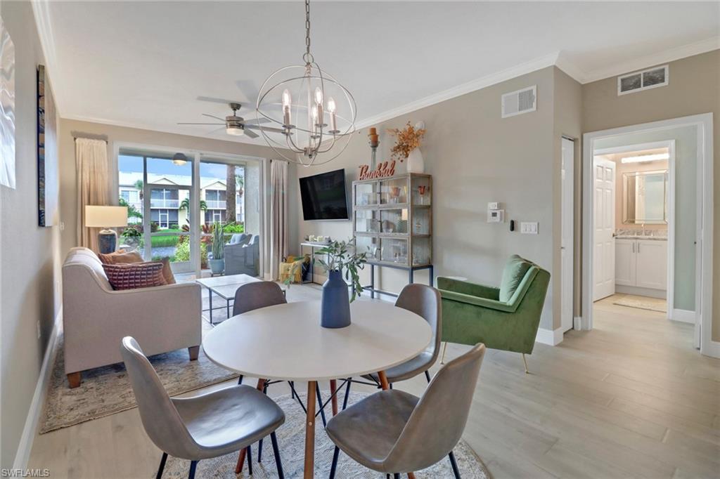 20261 Estero Gardens Circle, Unit 104 Estero, FL 33928 - Photo 9 of 50 Dining area featuring ceiling fan with notable chandelier, crown molding, and light wood-type flooring