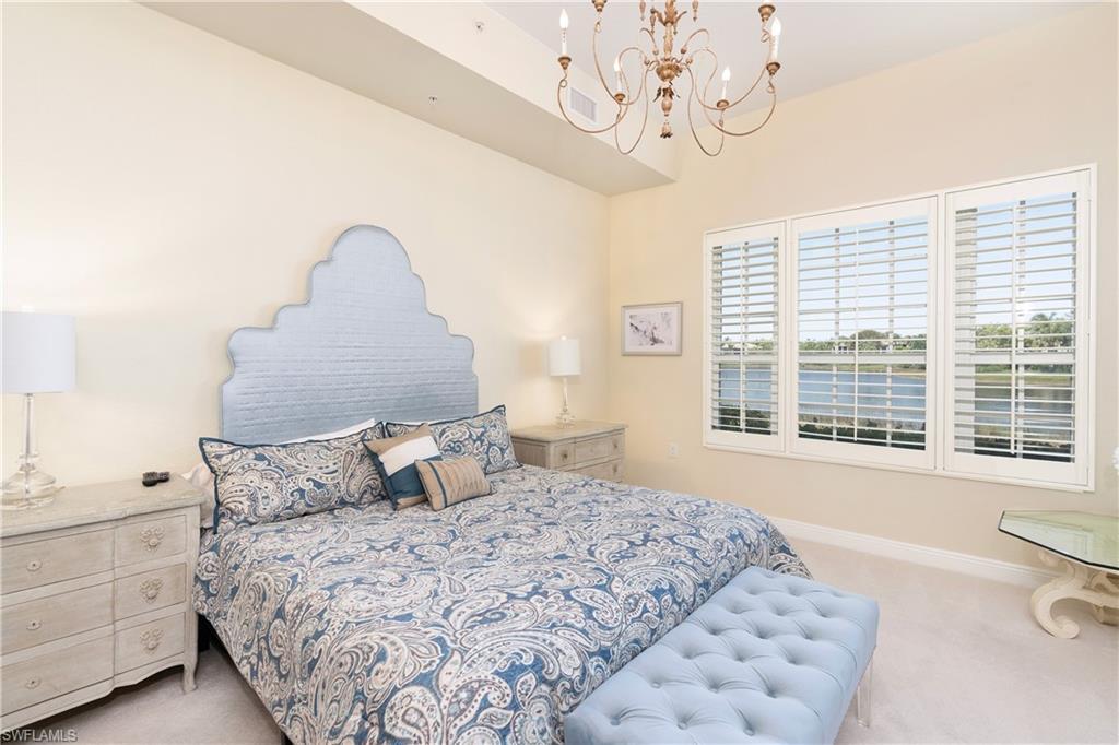 9259 Museo Circle, Unit 7102 Naples, FL 34114 - Photo 12 of 41 a bedroom with a large bed and a chandelier