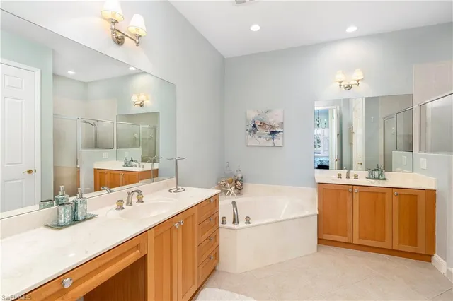 a bathroom with a tub a double vanity sink and mirror
