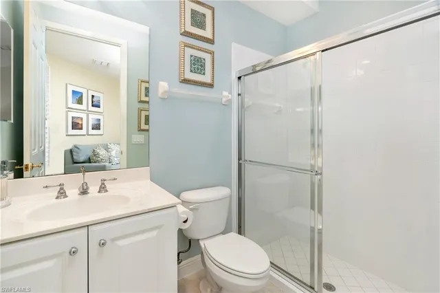 a bathroom with a shower sink vanity mirror and toilet