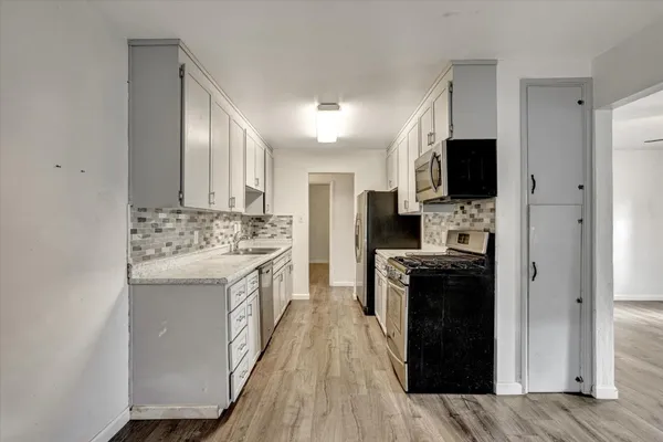 a kitchen with kitchen island stainless steel appliances a sink cabinets and a counter top space