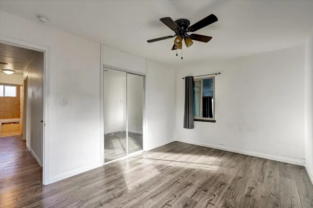 a view of empty room with wooden floor and fan