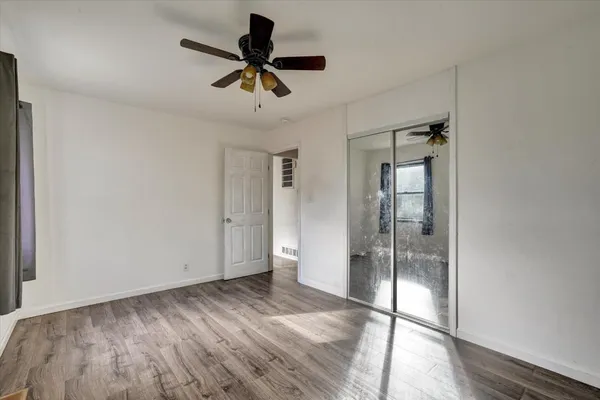 a view of empty room with wooden floor and fan
