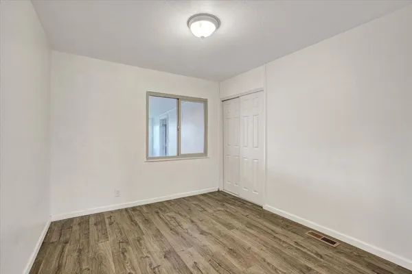 an empty room with wooden floor and windows