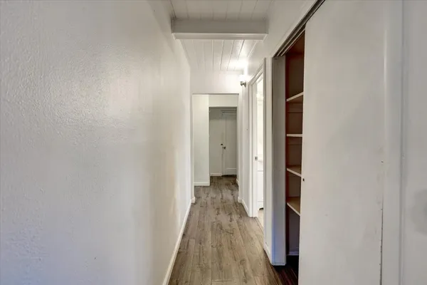 a view of a hallway with wooden floor and a bathroom