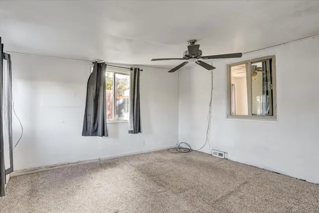 an empty room with windows and fan