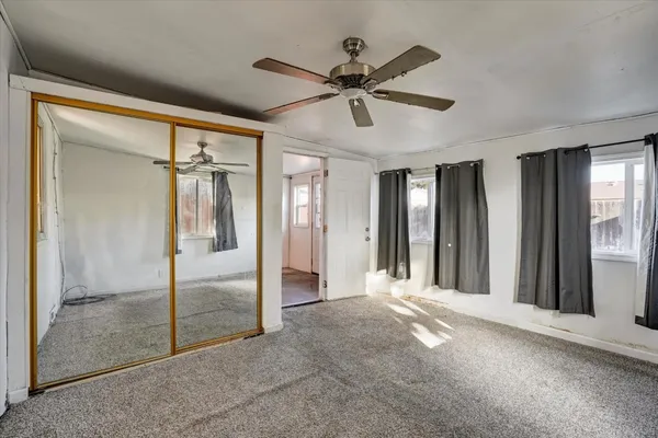 a view of a livingroom with a chandelier fan and windows