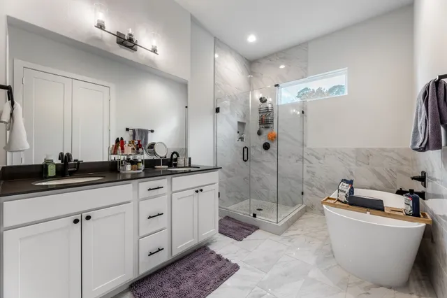 a bathroom with a granite countertop sink a toilet a mirror and shower