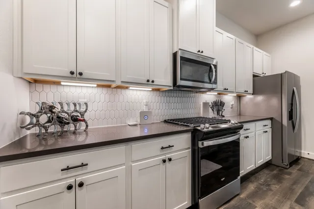 a kitchen with stainless steel appliances granite countertop white cabinets stove a sink and dishwasher