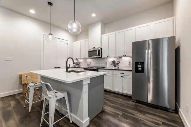 a kitchen with granite countertop a refrigerator a stove a microwave oven a sink and dishwasher with wooden floor