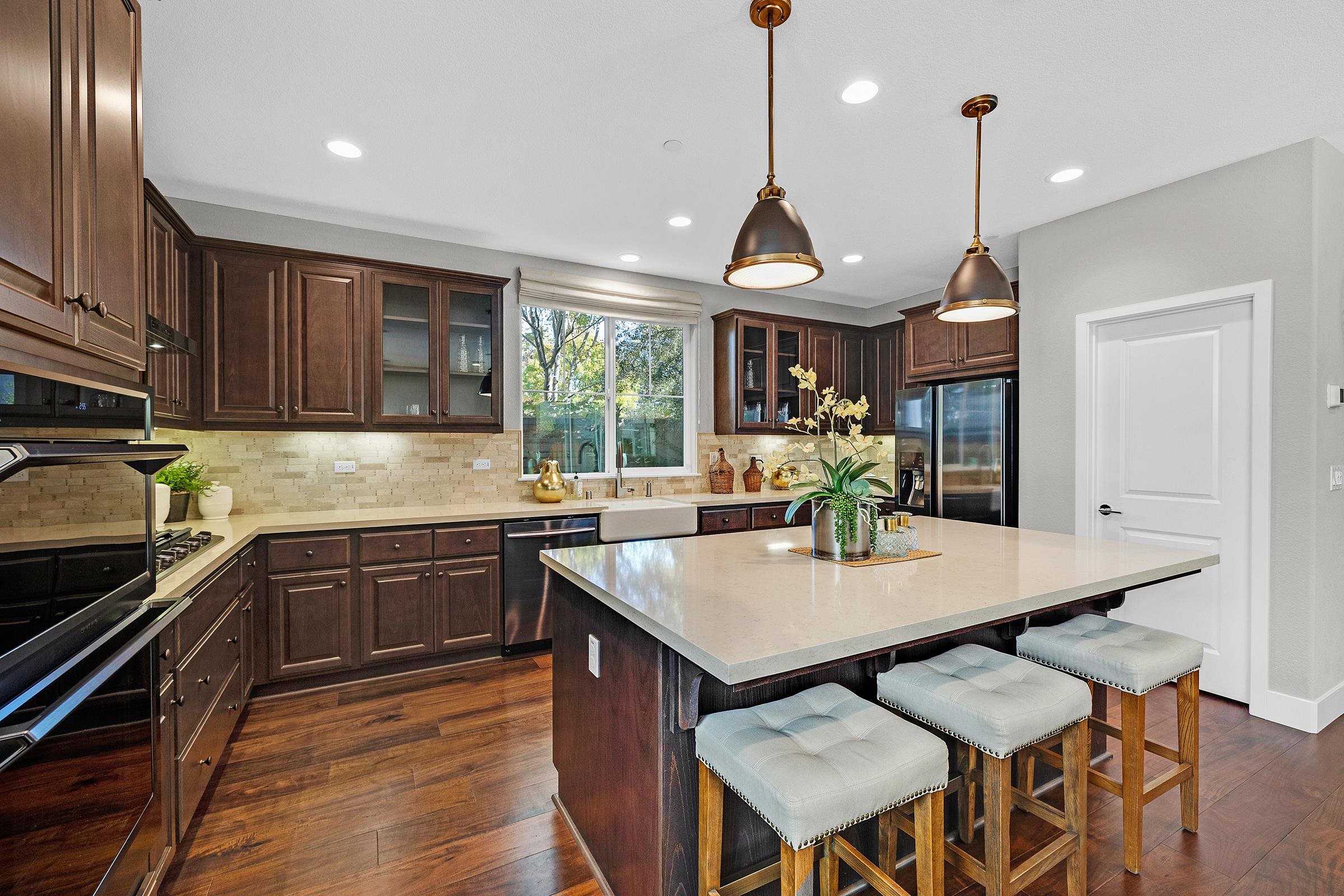 883 Barney Common Livermore, CA 94551 - Photo 3 of 38 a kitchen with stainless steel appliances granite countertop a kitchen island a stove a table and chairs with wooden floor