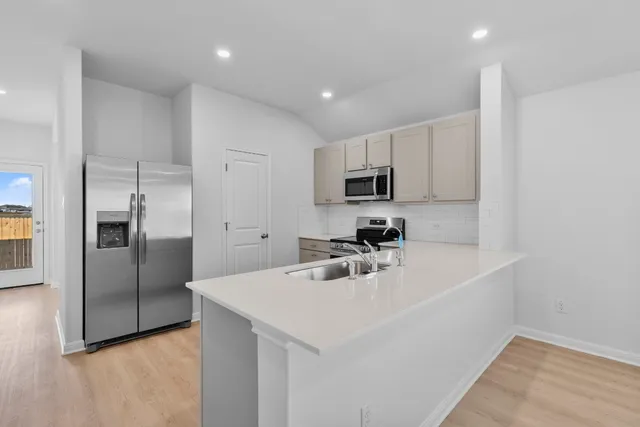 a kitchen with kitchen island a sink stainless steel appliances and cabinets