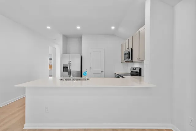 a large white kitchen with kitchen island sink and refrigerator
