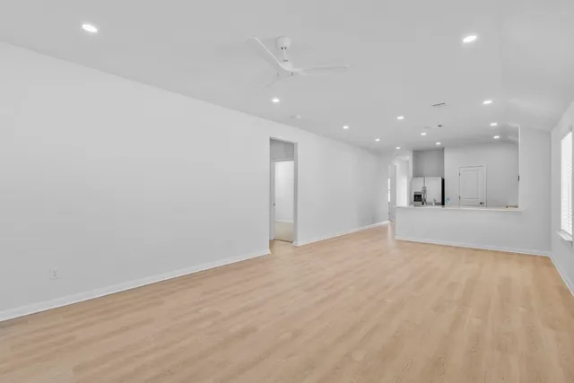 a view of an empty room with kitchen counter space and wooden floor