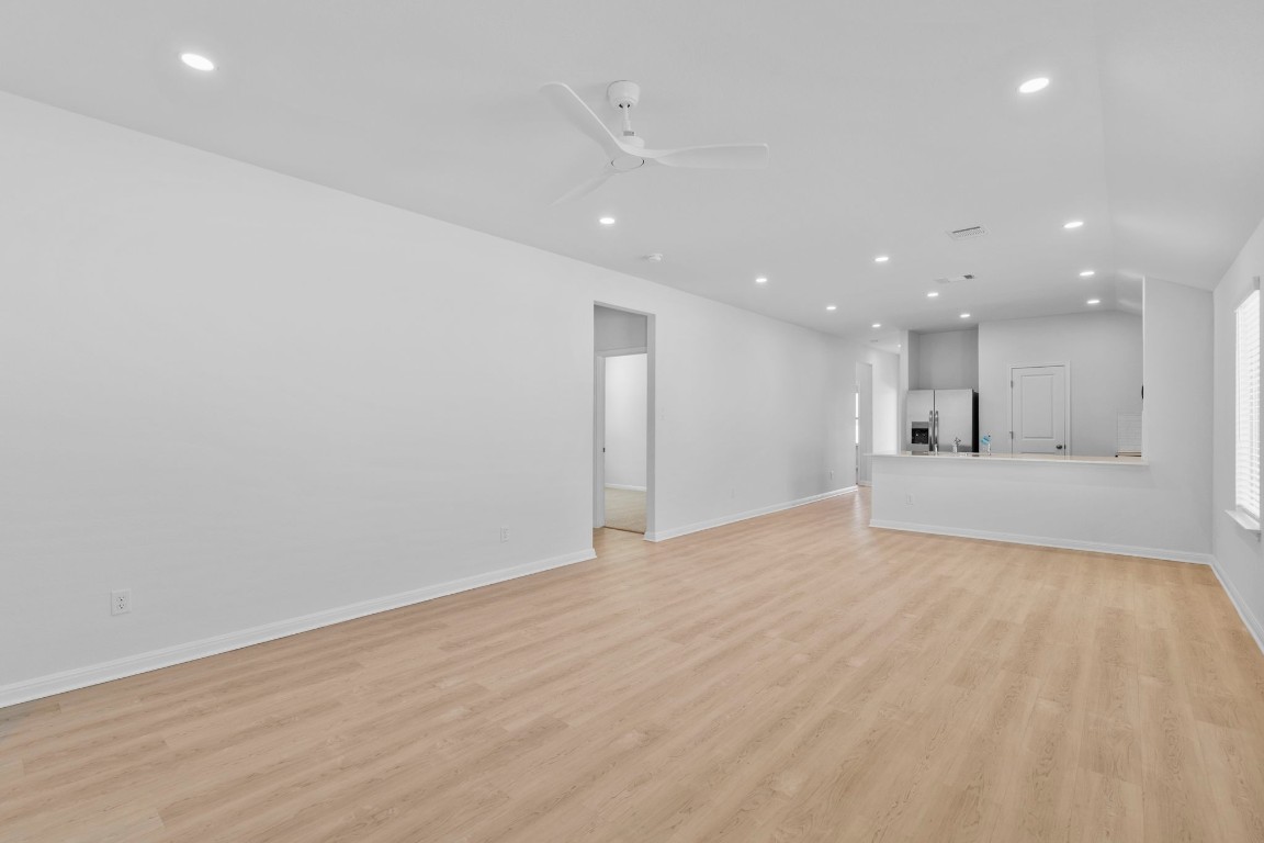 129 Hatari Trail Jarrell, TX 76537 - Photo 6 of 33 a view of an empty room with kitchen counter space and wooden floor