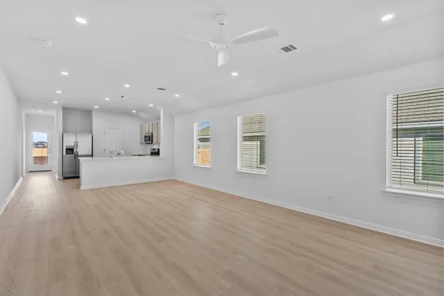 a view of an empty room with a window and wooden floor