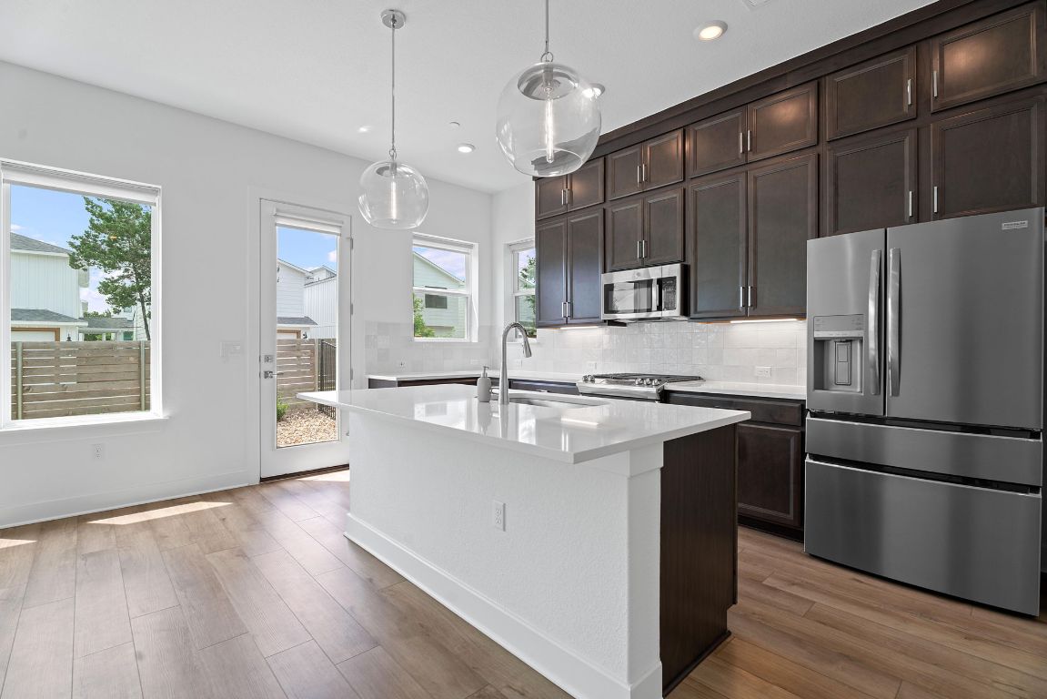 a kitchen with kitchen island a counter top space stainless steel appliances and a window