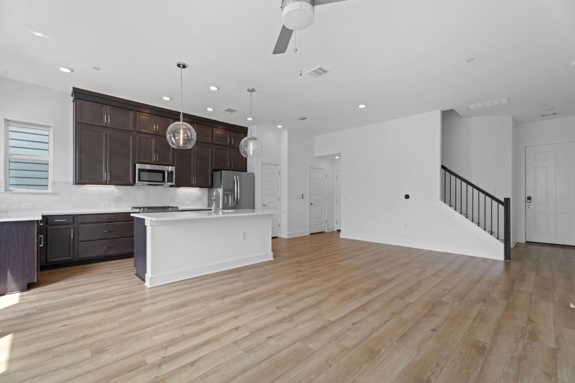 609 Terrier Trail Austin, TX 78745 - Photo 24 of 26 a large white kitchen with a large counter top stainless steel appliances and wooden floor