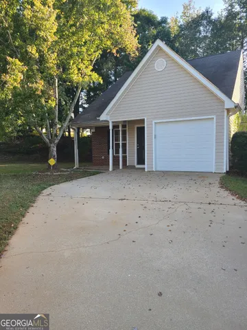 a front view of a house with a garden and trees