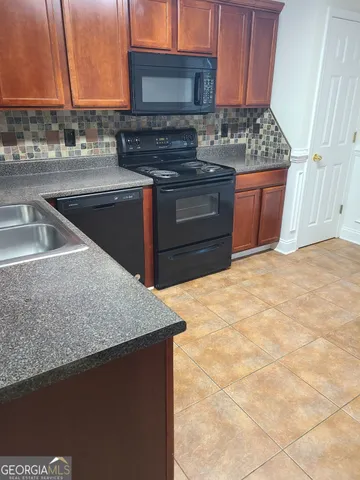 a kitchen with granite countertop a stove a sink and a microwave