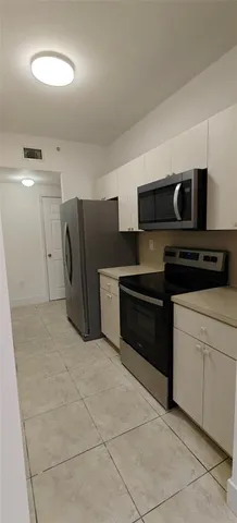 a kitchen with granite countertop a refrigerator and a stove top oven