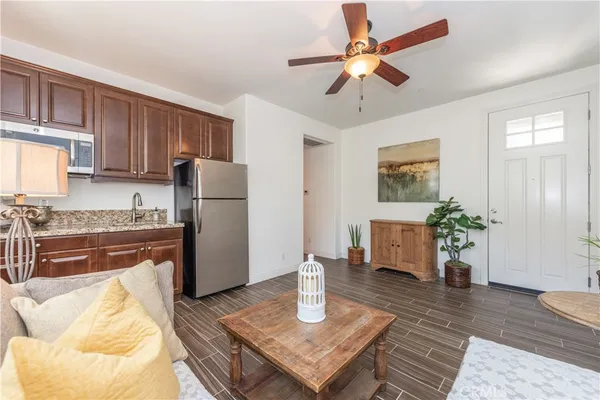 a living room with stainless steel appliances furniture a rug and a window