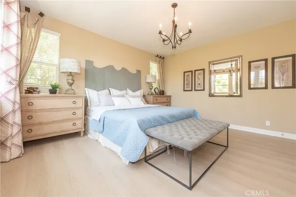 a bedroom with a bed chandelier and a window