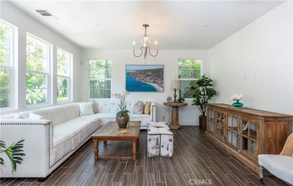 a living room with furniture a chandelier and wooden floor