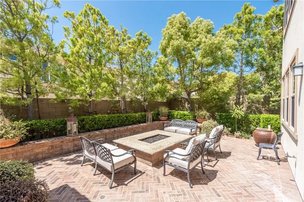 a view of a patio with table and chairs and potted plants with large tree