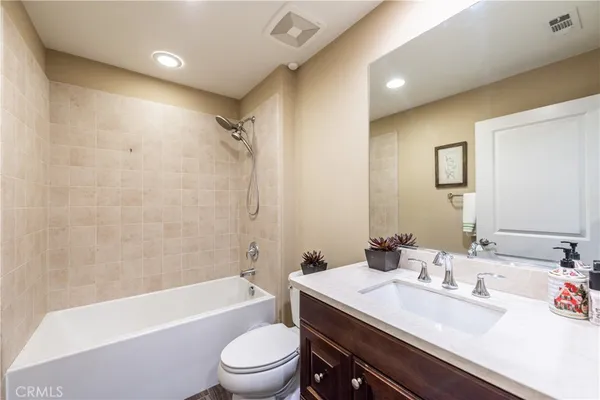 a bathroom with a granite countertop sink a toilet a mirror a bathtub and shower