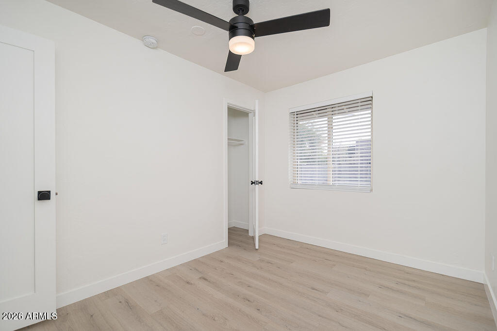 4653 East Almeria Road Phoenix, AZ 85008 - Photo 12 of 18 an empty room with wooden floor ceiling fan and windows