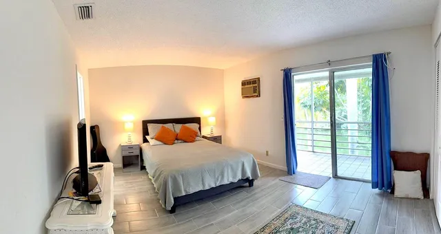 a bedroom with a bed a mirror and wooden floor