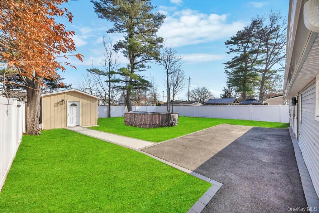 111 Blacksmith Road East Levittown, NY 11756 - Photo 14 of 14 Fenced backyard featuring a pool, a patio area, and an outbuilding