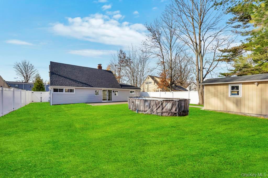 111 Blacksmith Road East Levittown, NY 11756 - Photo 3 of 14 Rear view of house featuring a fenced backyard and a chimney