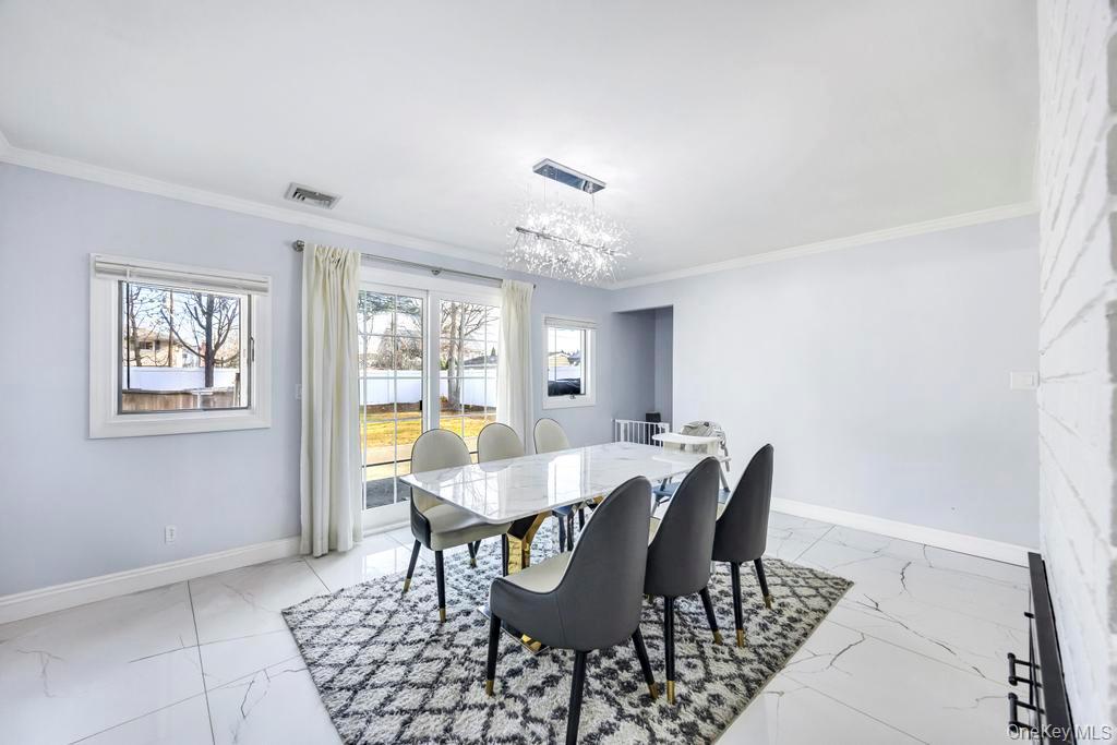 111 Blacksmith Road East Levittown, NY 11756 - Photo 5 of 14 Dining space featuring ornamental molding, light marble finish flooring, and a chandelier