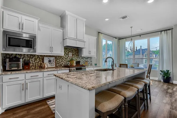 a kitchen with granite countertop a sink chairs and cabinets