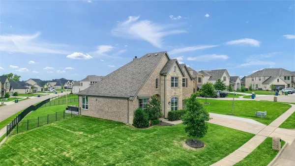 a view of a house next to a big yard and large trees