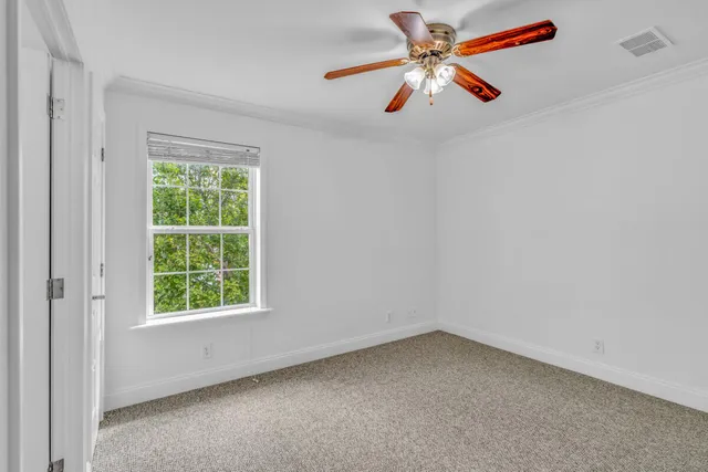 an empty room with ceiling fan and window