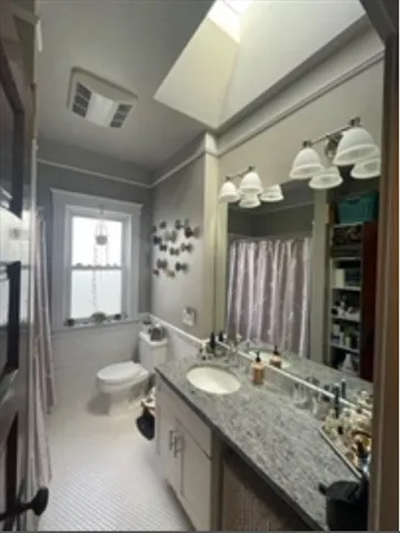 a bathroom with a granite countertop sink a toilet and shower