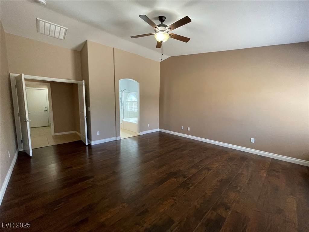 92 Whitetail Archery Avenue North Las Vegas, NV 89084 - Photo 17 of 33 Unfurnished bedroom with dark wood-style floors, arched walkways, a ceiling fan, connected bathroom, and vaulted ceiling