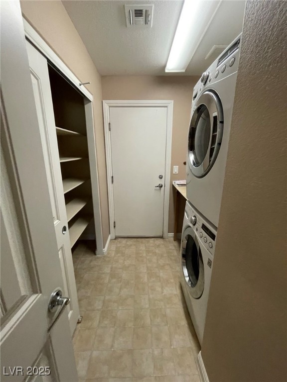92 Whitetail Archery Avenue North Las Vegas, NV 89084 - Photo 28 of 33 Laundry area with stacked washer and clothes dryer and a textured ceiling